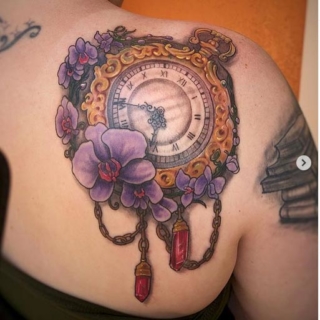 Tattoo: antique pocketwatch surrounded by purple flowers and pink jewels
