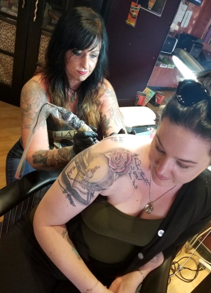 Dawn Webb uses her creative talent to tattoo the shoulder of a customer.